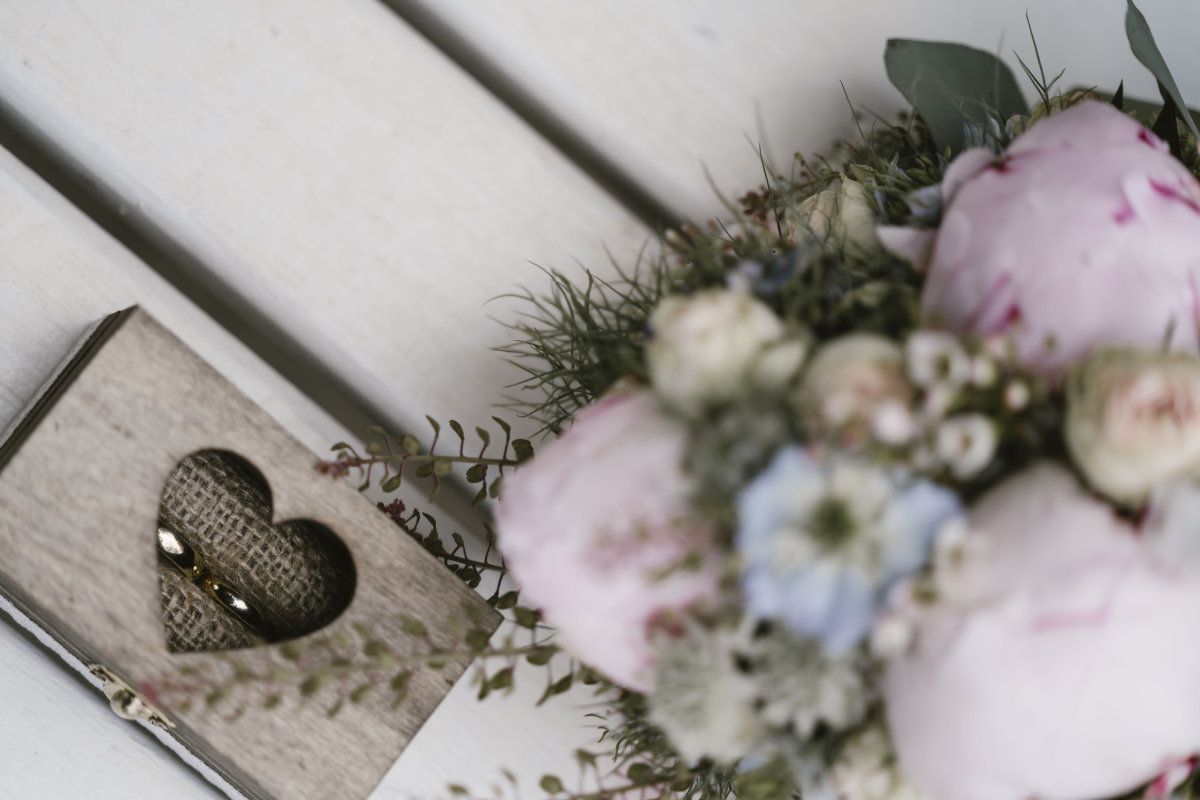 Brautstrauß und Eheringe in Holzbox von oben fotografiert