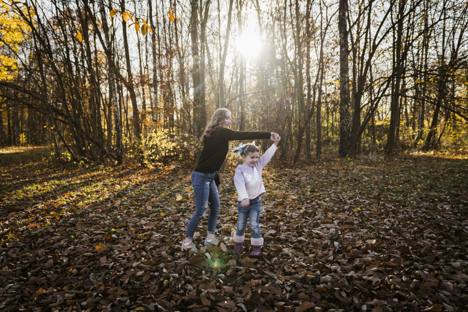 Mutter und Tochter tanzend im Wald bei einem Herbstshooting 