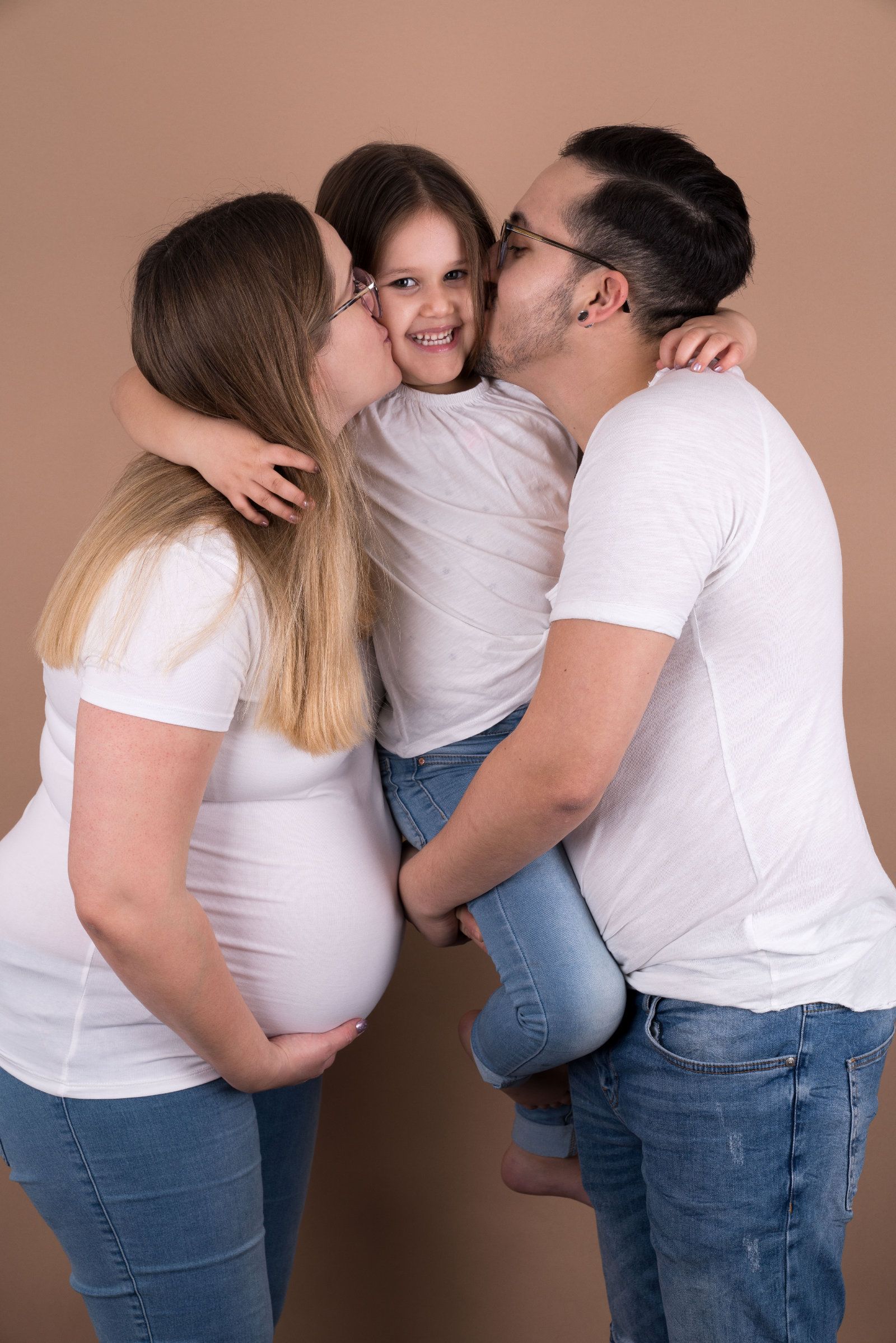 Schwangere und Vater küssen ihre Tochter auf die Wange
